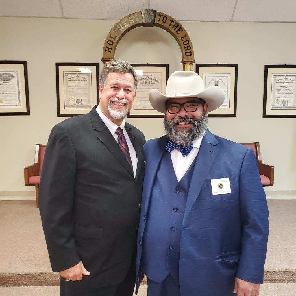Two Brethren posing in front of framed Lodge certificates